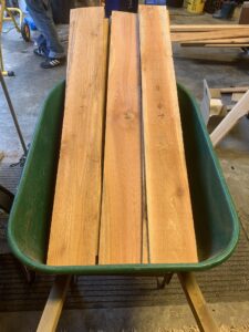 Stacks of fresh cut boards in a green wheelbarrow.