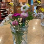 A glass mason jar filled with a bouquet of colorful wildflowers.